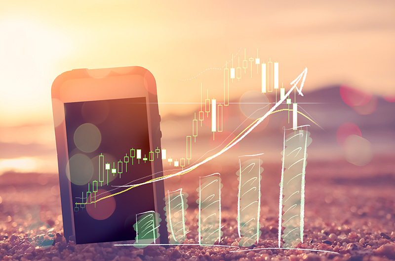 Phone on beach with summer marketing graph showing positive results.