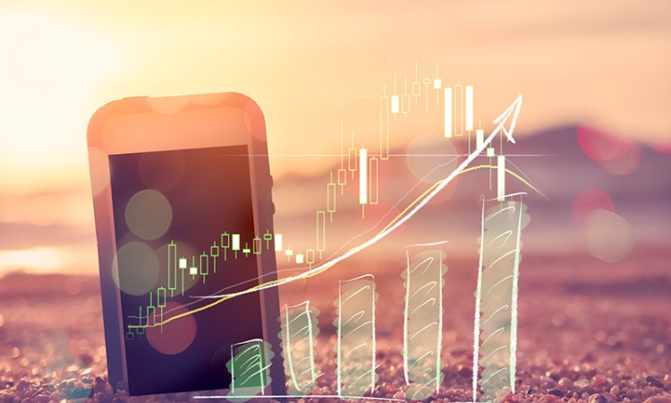 Phone on beach with summer marketing graph showing positive results.