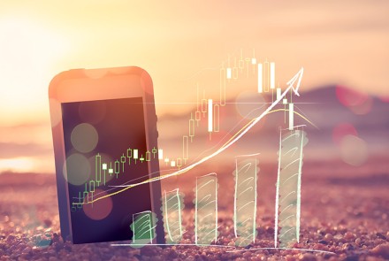 Phone on beach with summer marketing graph showing positive results.